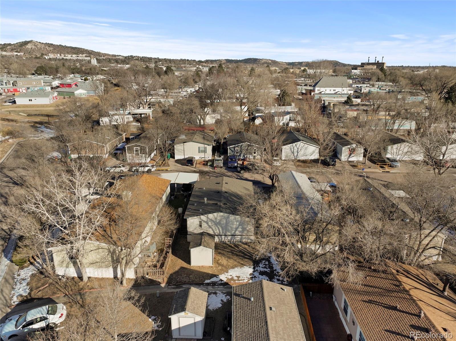 Aerial view of homes and leafless trees in a neighborhood, with hills beyond.