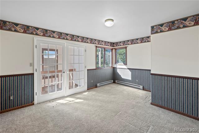 Vacant carpeted room with French doors and blue striped wainscoting.