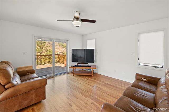 Living room with hardwood floors, leather sofas, and sliding glass doors opening onto a deck.