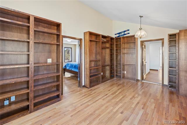 Office lined with built-in wood bookshelves and hardwood flooring, with a blue bed visible through the doorway.