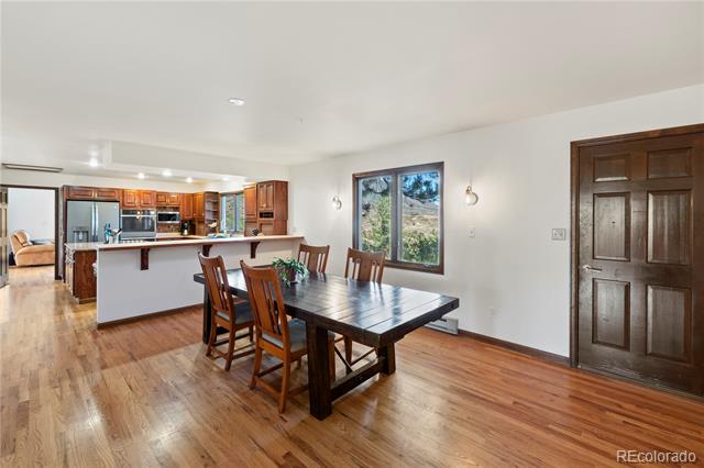 Dining area with a dark wood table, hardwood floors, and an open kitchen with wood cabinets.