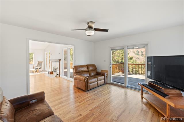 Living room with hardwood floors, brown leather seating, and sliding doors to a deck.