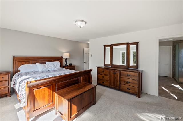Bedroom with a dark wood bed and matching dresser and mirror, lit by sunlight.