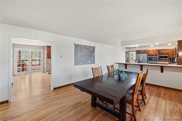 Dining room with a dark wood table, hardwood floors, and an adjoining kitchen.