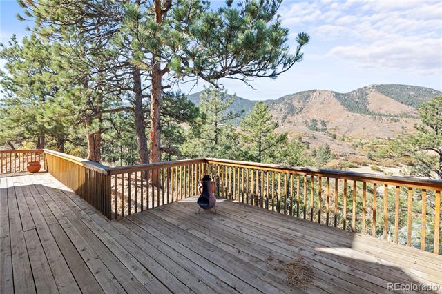 Wooden deck with a chiminea overlooking pine trees and mountains.