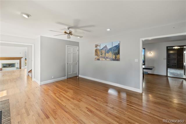 Unfurnished room with hardwood floors, gray walls, and open doorways to adjoining rooms.