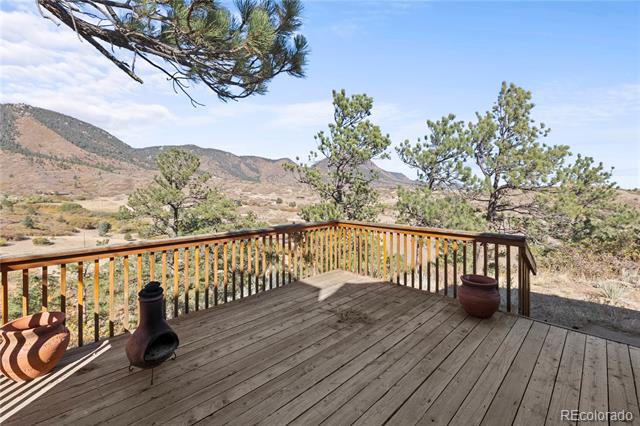 Wooden deck overlooking foothills, with a chiminea and potted plants.