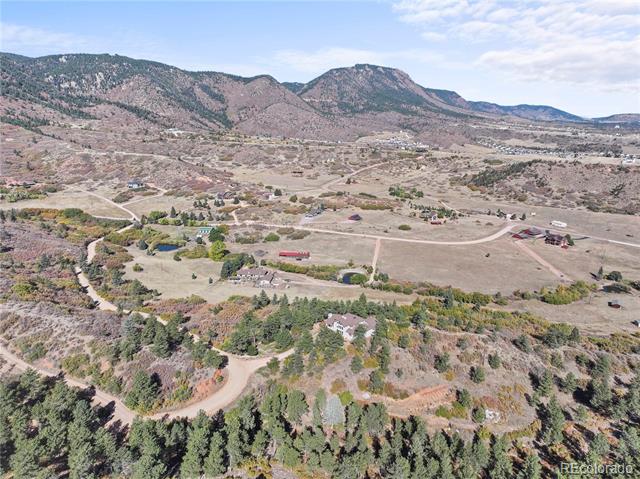 Aerial view of open residential land, winding roads, scattered homes, and mountains.
