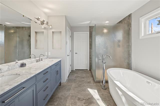 Bathroom with blue-gray double vanity, glass shower, and freestanding soaking tub.