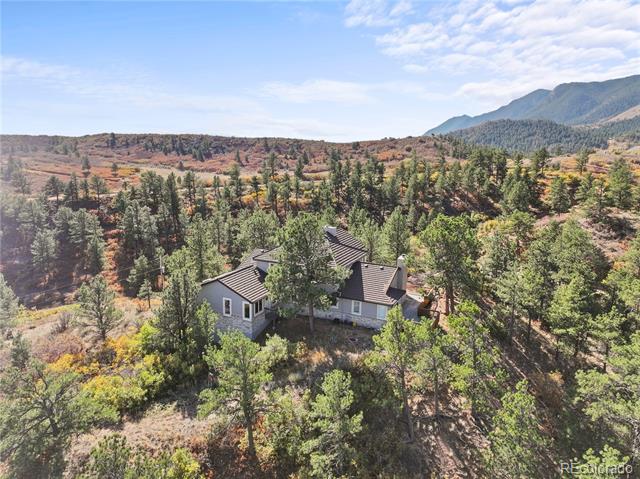 Aerial view of a home surrounded by autumn trees, with mountains in the distance.