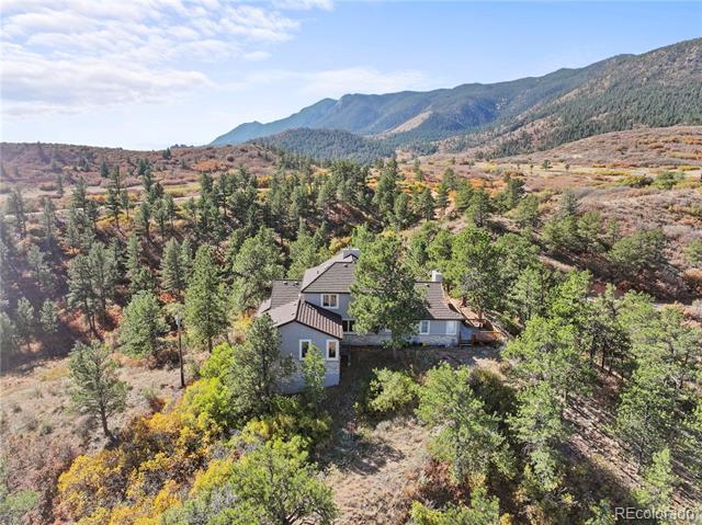 Aerial view of a mountain home surrounded by trees and autumn-colored foothills.