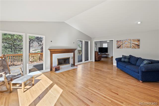 Living room with a wood-trimmed fireplace, blue sofa, and sunlit hardwood floors.