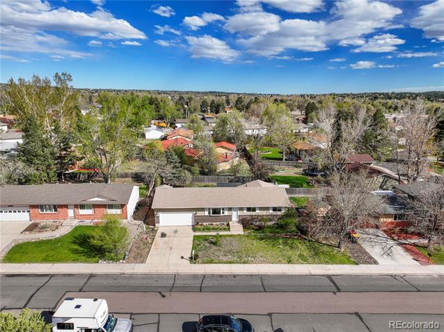 Aerial view of a single-story home with an attached garage and fenced yard on a residential street.