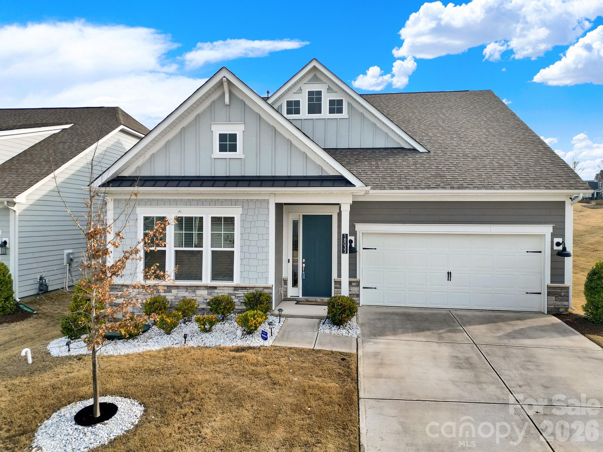 Gray-and-white gabled house with a blue front door, white garage, and concrete driveway.