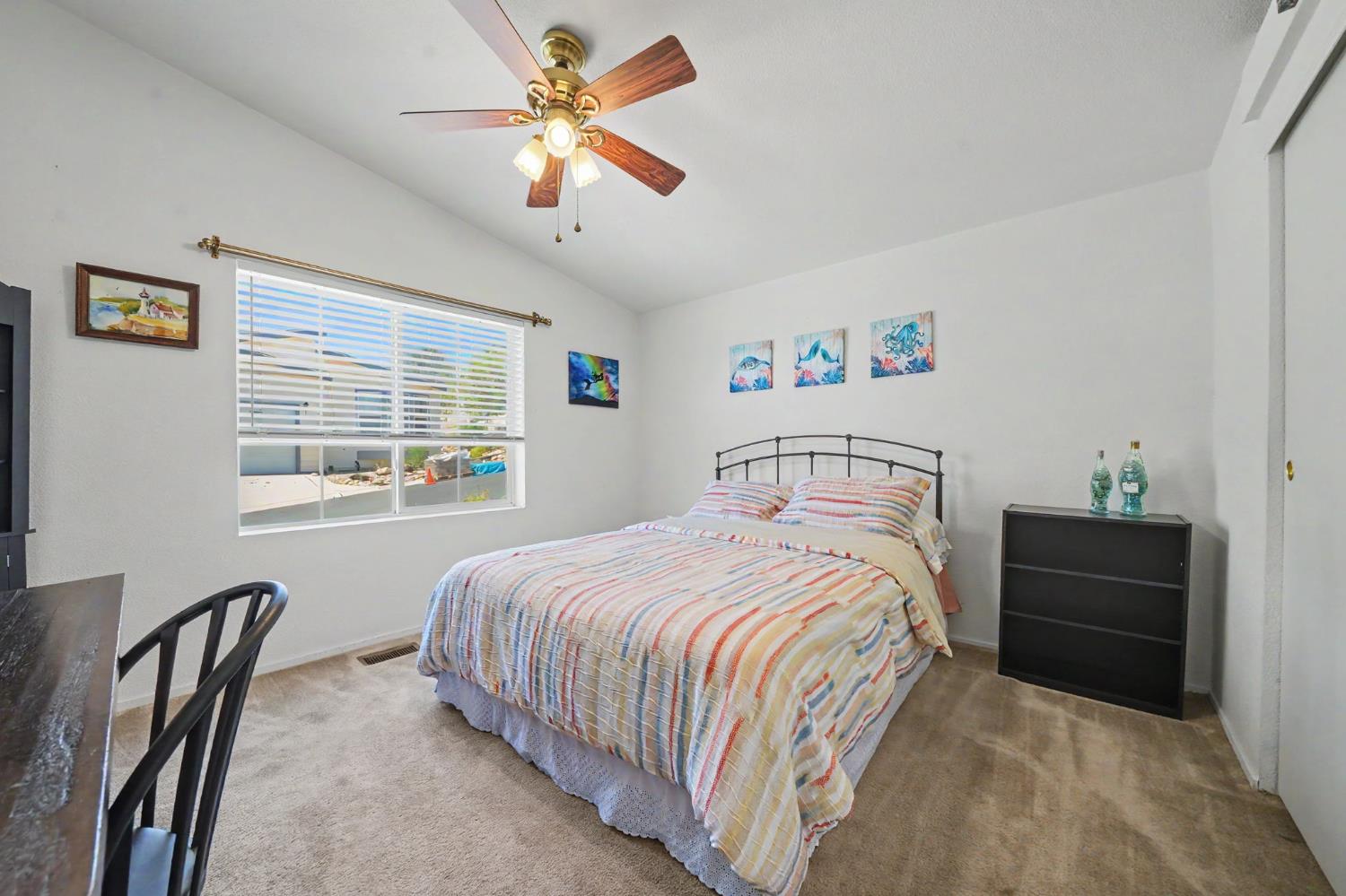 Bedroom with a striped comforter, black metal headboard, and ceiling fan.