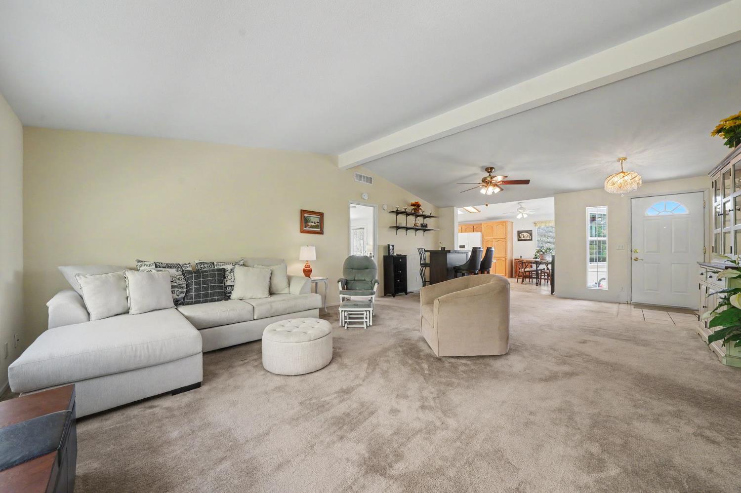 Living room with a light sectional sofa, beige carpet, and open dining and kitchen areas.