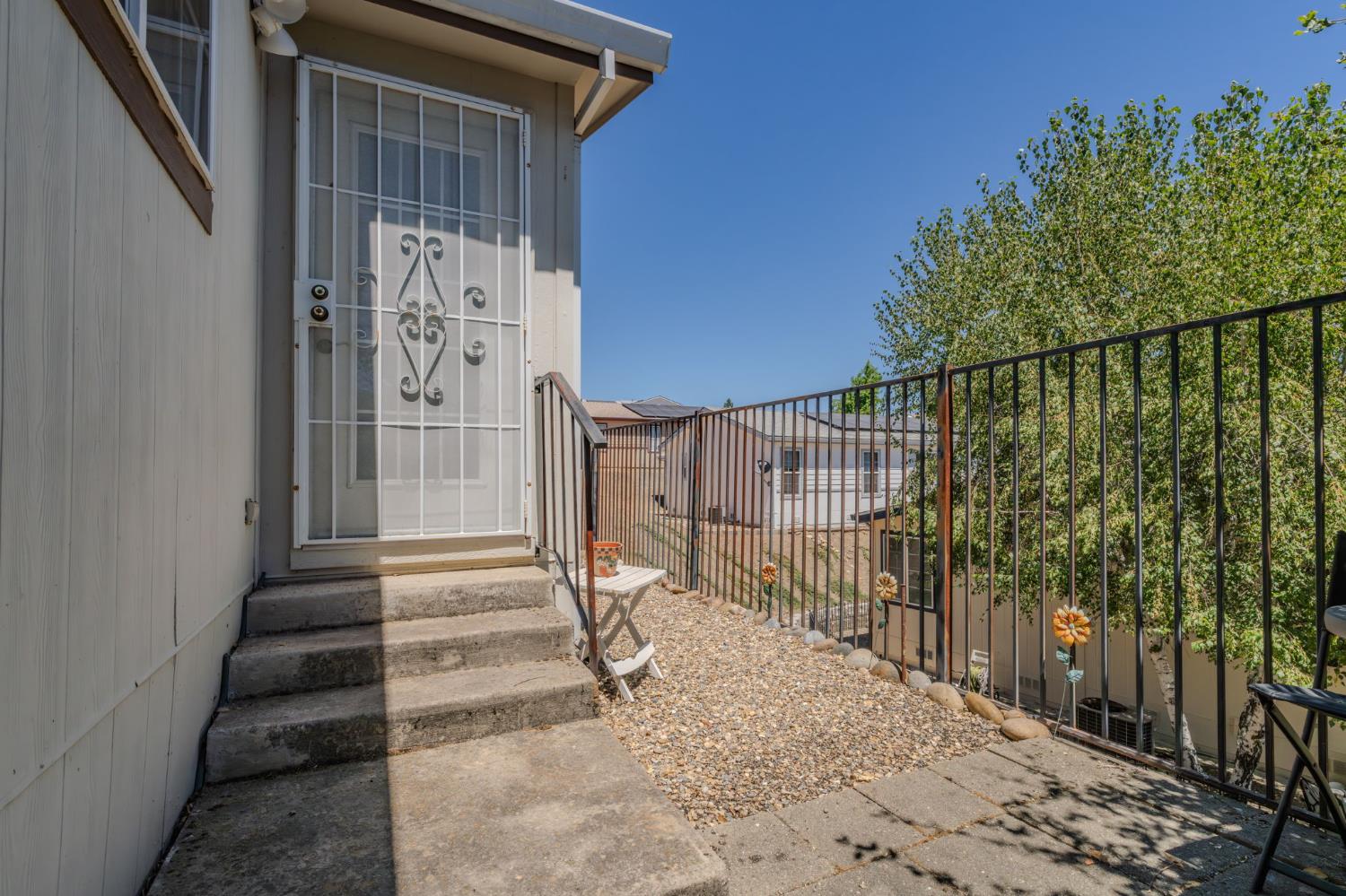 Gravel patio with concrete steps, a barred sliding door, and black metal railing.
