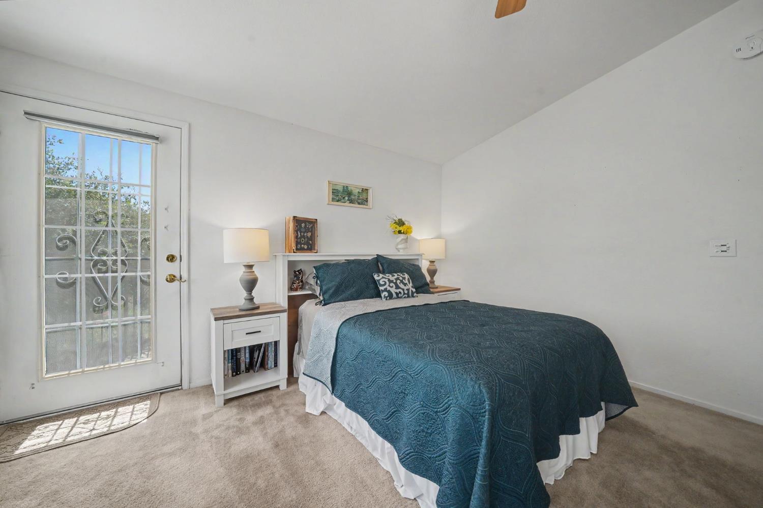 Bedroom with a teal-covered bed beside a glass-paneled door.