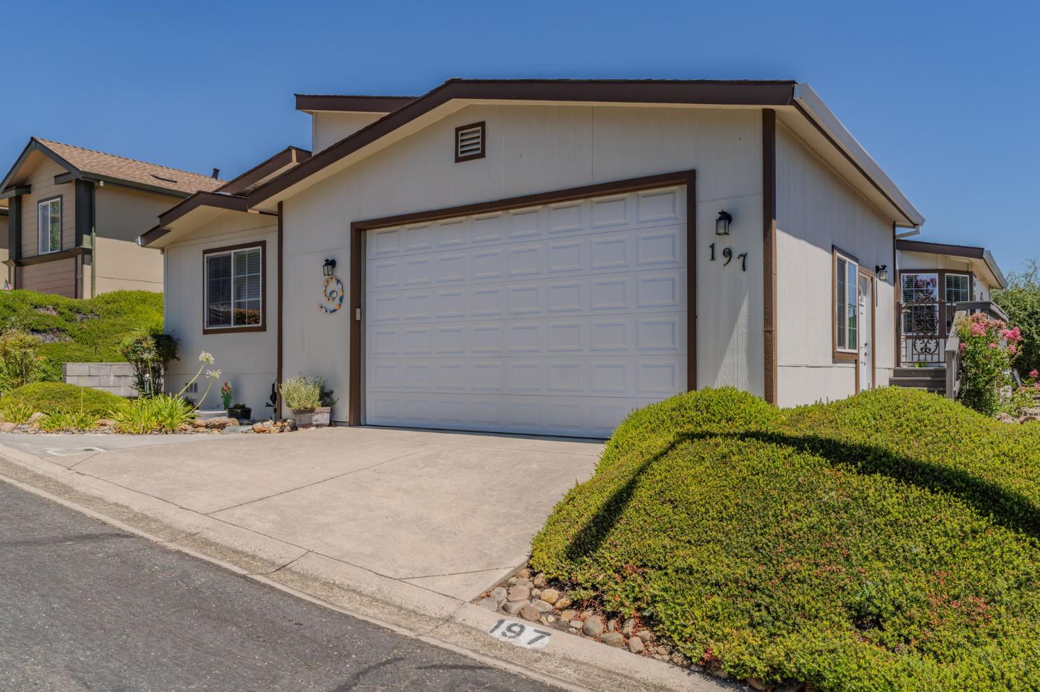 Home exterior with a large white garage door, landscaped shrubs, and 197 marked on the curb.