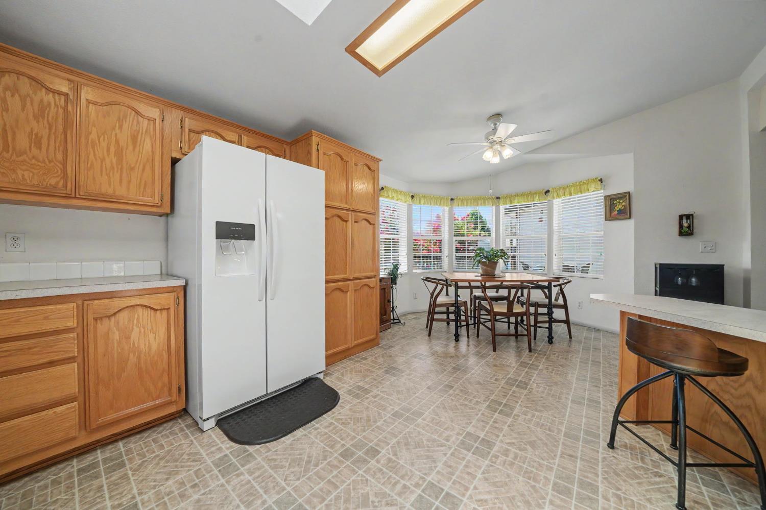 Kitchen with wood cabinets, patterned tile floors, and a dining table beside bay windows.