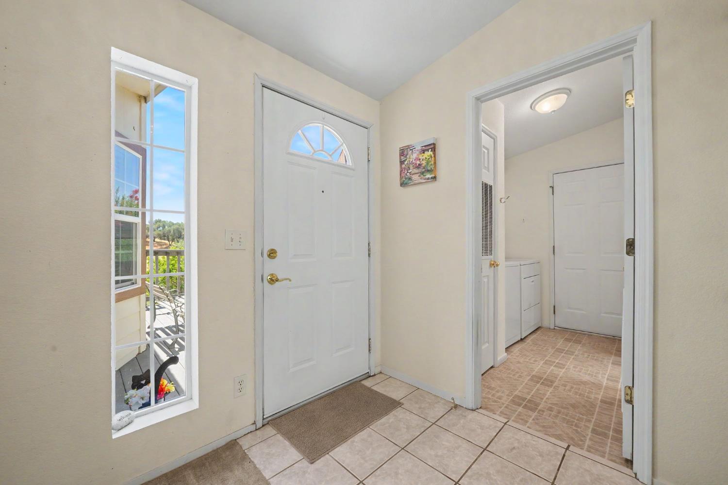 Entry foyer with a white front door, tiled floor, and window overlooking the porch.