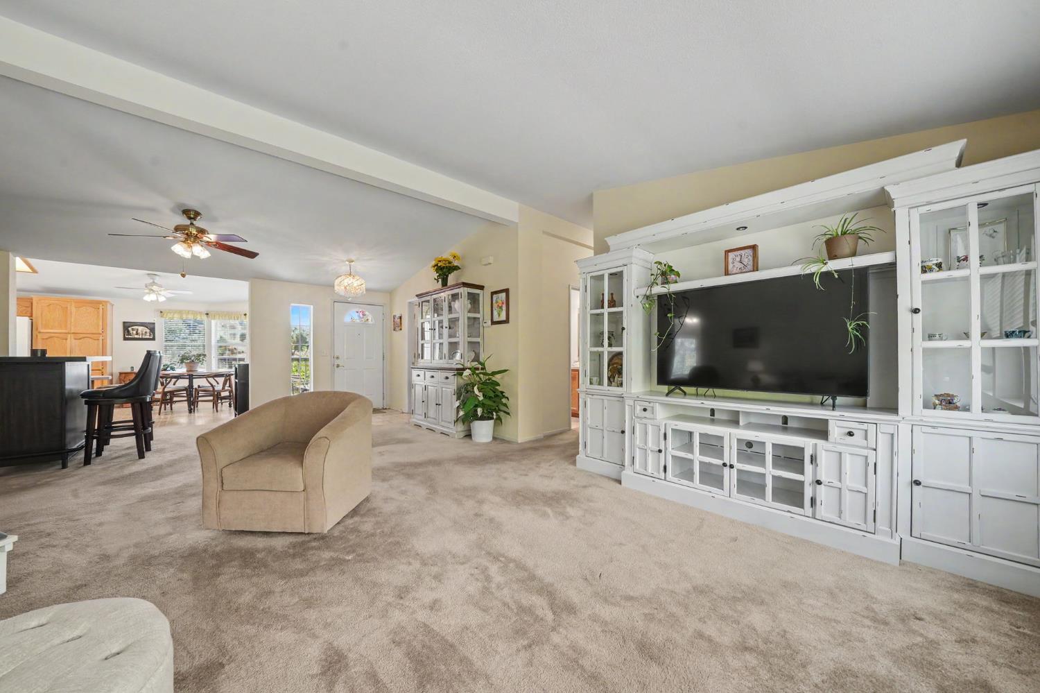 Furnished living room with a white built-in entertainment center and an open view to the dining area.