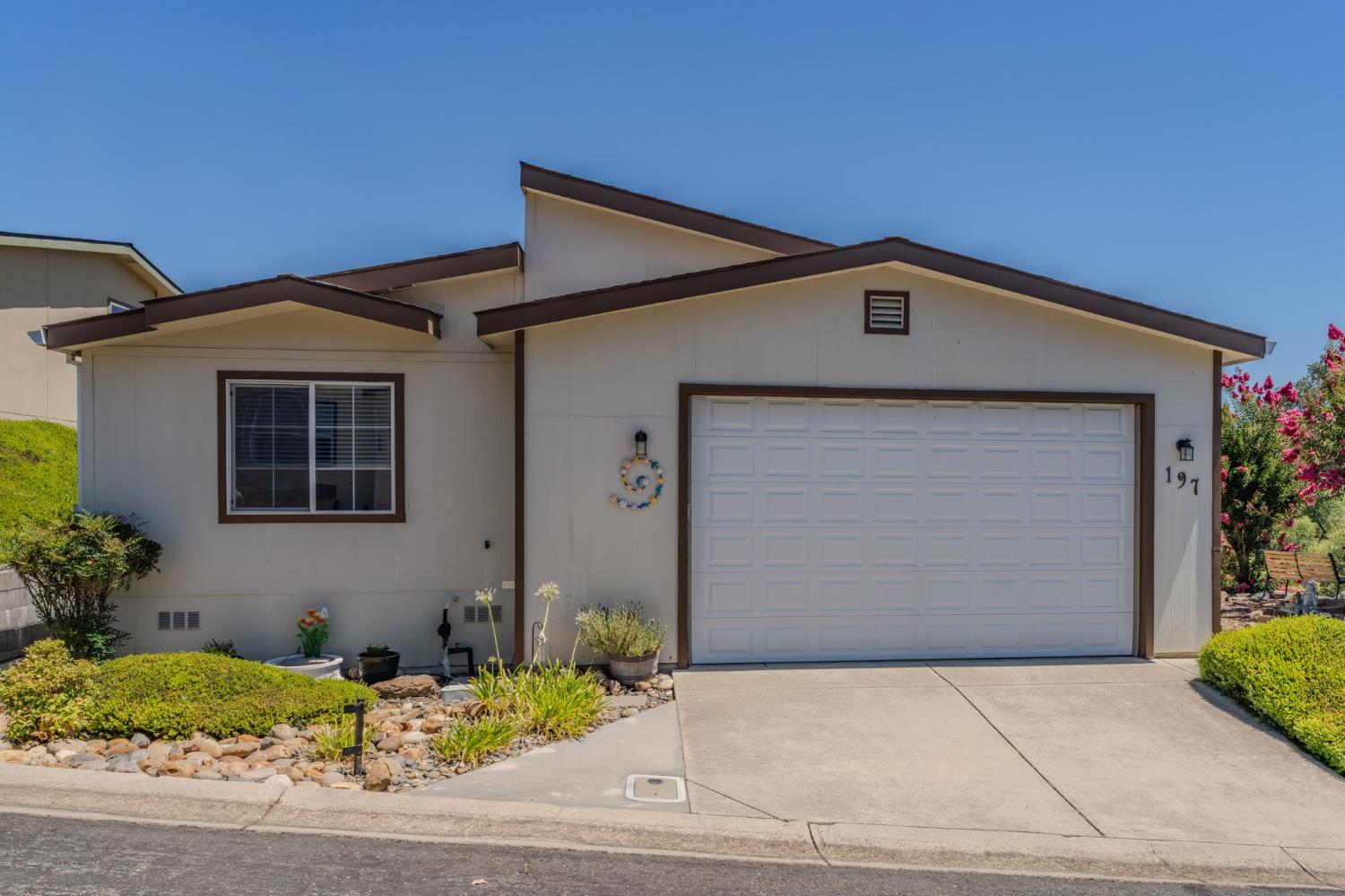 Single-story home with a wide garage, landscaped rock beds, and house number 197 beside the garage.