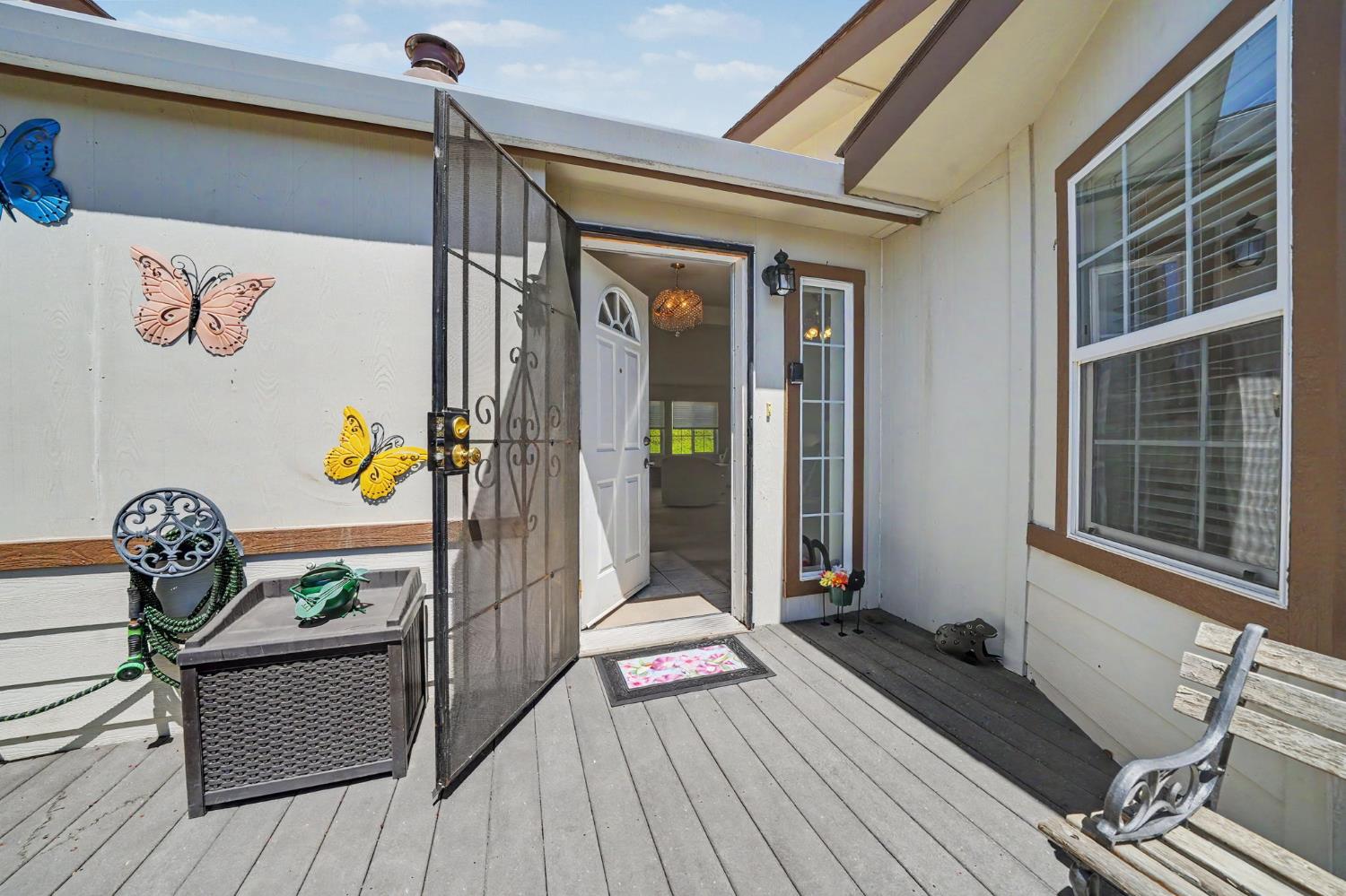 Front entry porch with gray decking, an open doorway, and butterfly decorations on the wall.