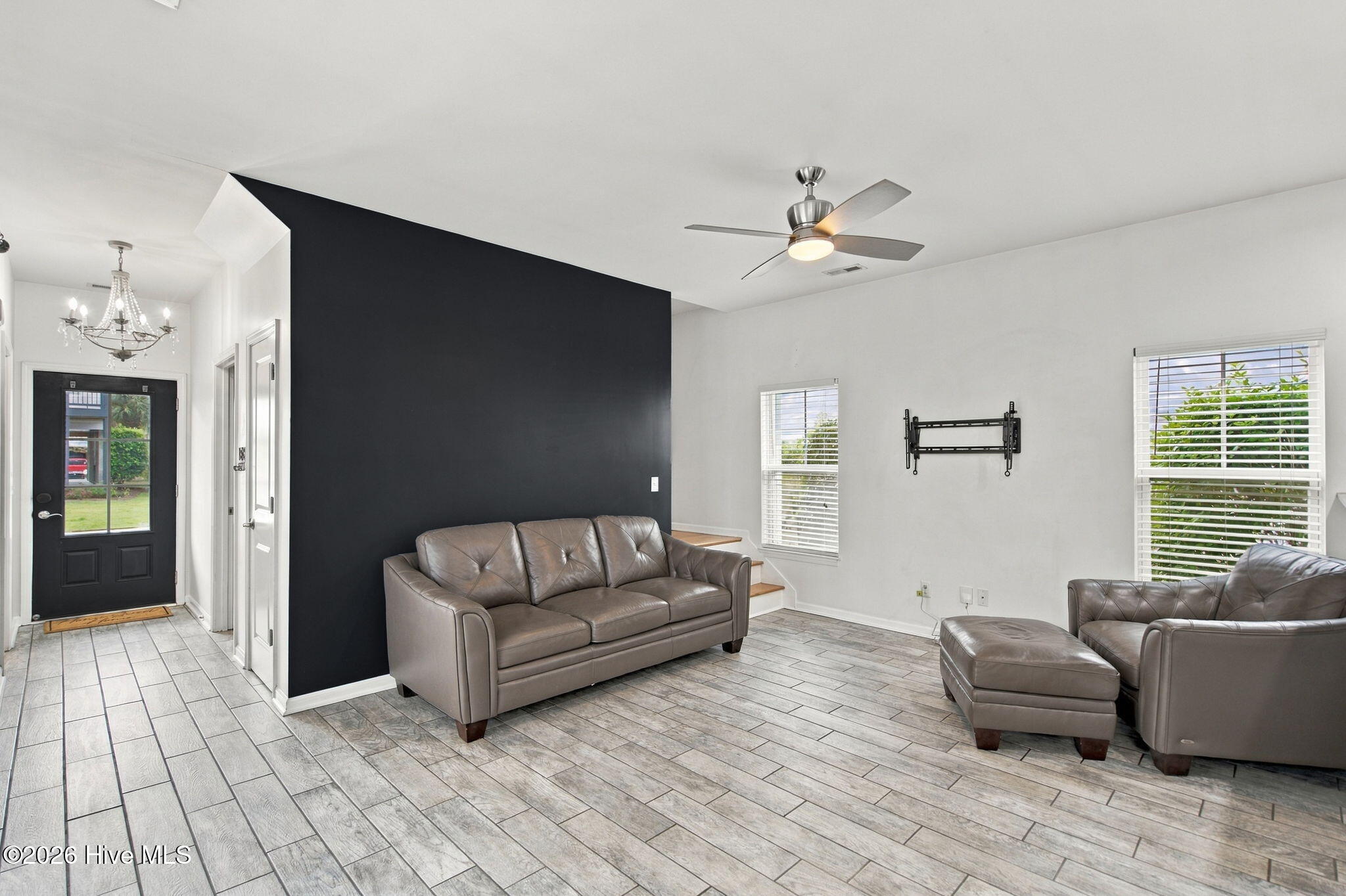 Living room with gray leather sofas, a dark accent wall, and large gray tile flooring.