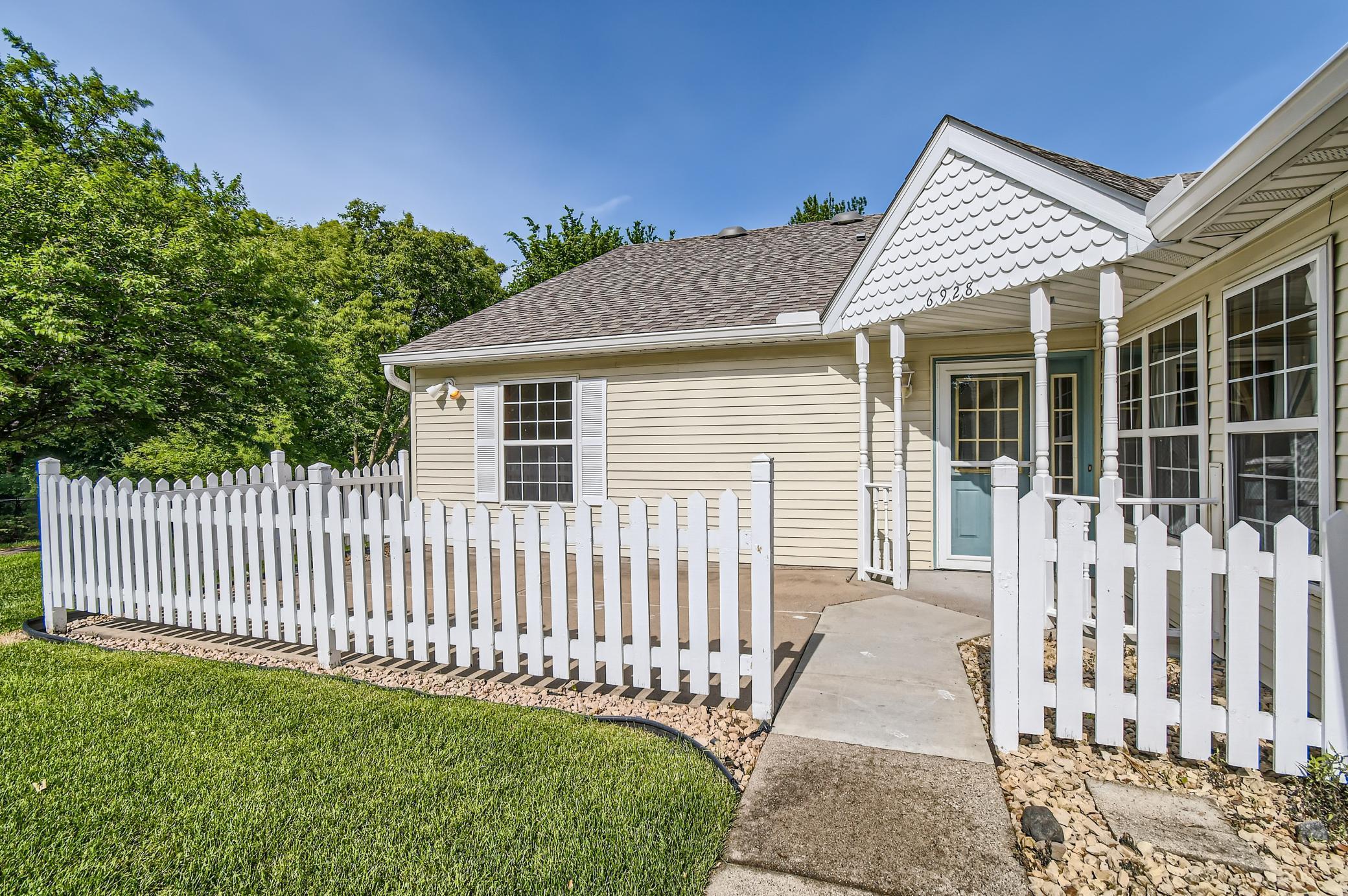 Home exterior with covered entry, fenced patio, and concrete walkway.