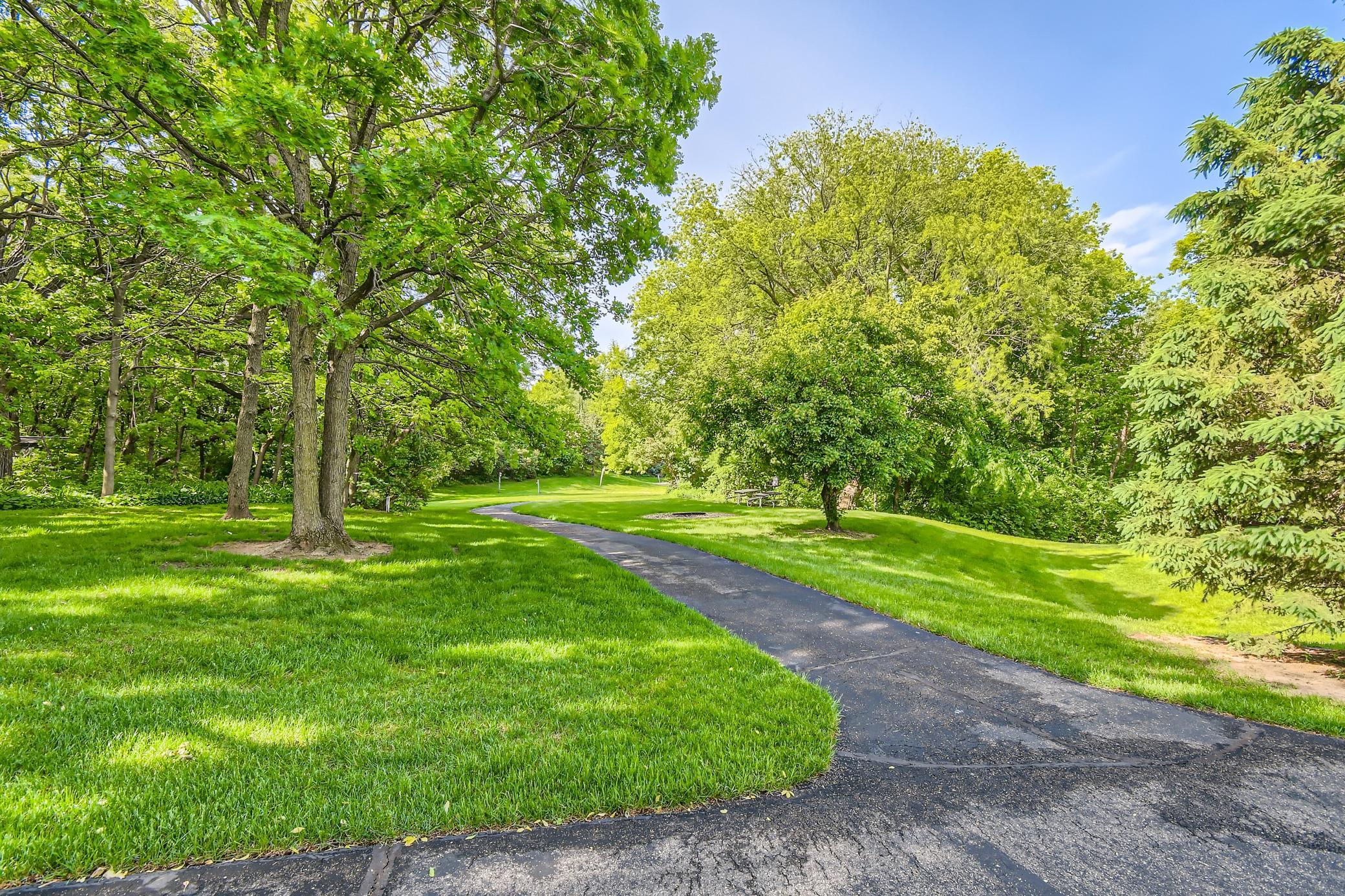 Landscaped grounds with mature trees, a broad lawn, and a curved asphalt driveway.