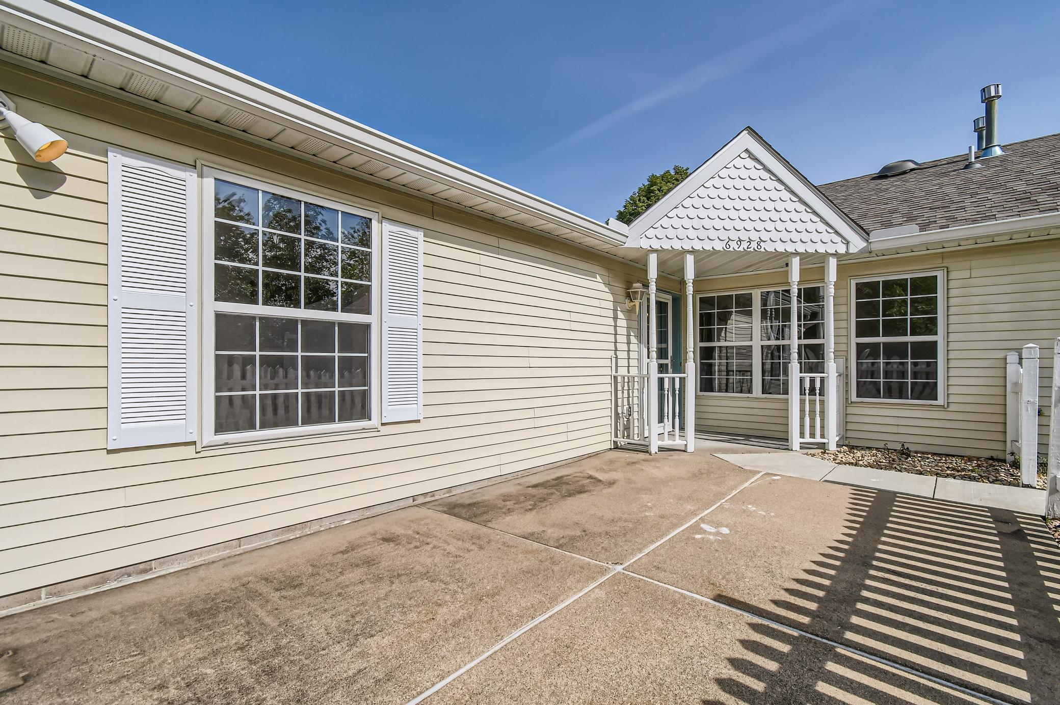 Home exterior with a concrete patio, shuttered windows, and a small covered entry.