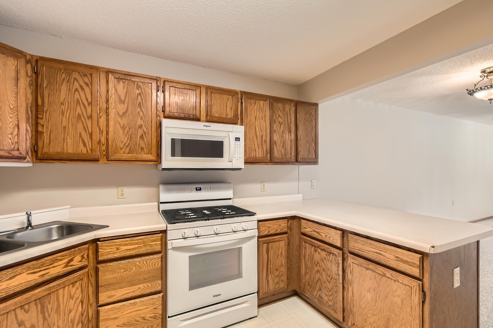 Kitchen with oak cabinets, light countertops, and white range and microwave.