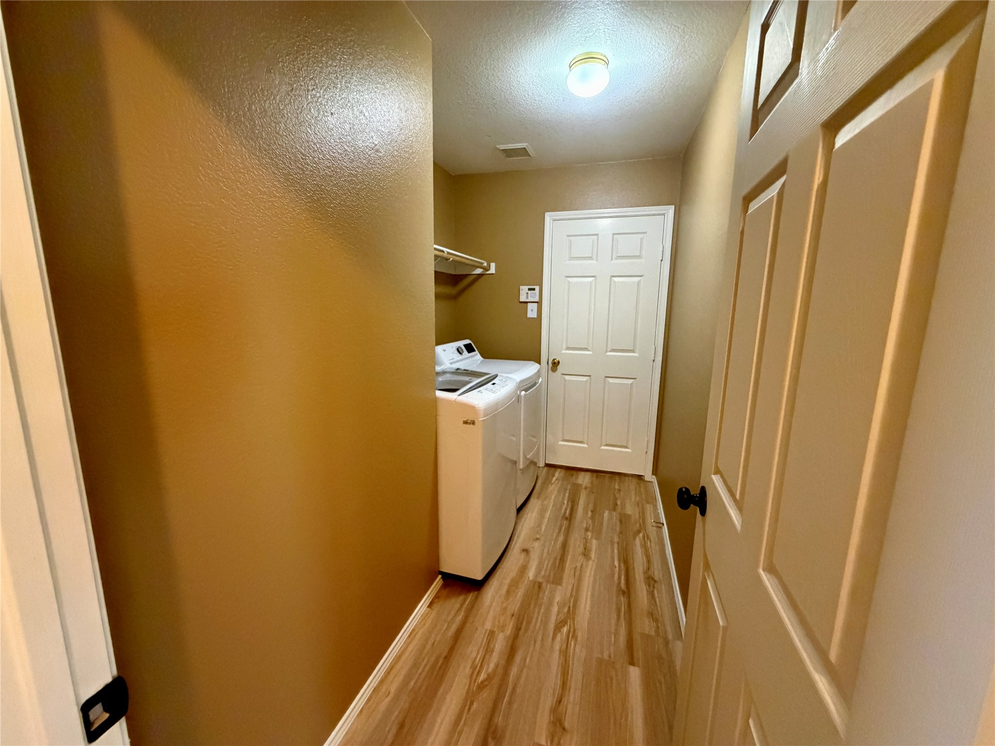 Laundry room with washer and dryer, a hanging rod, and wood-look plank flooring.