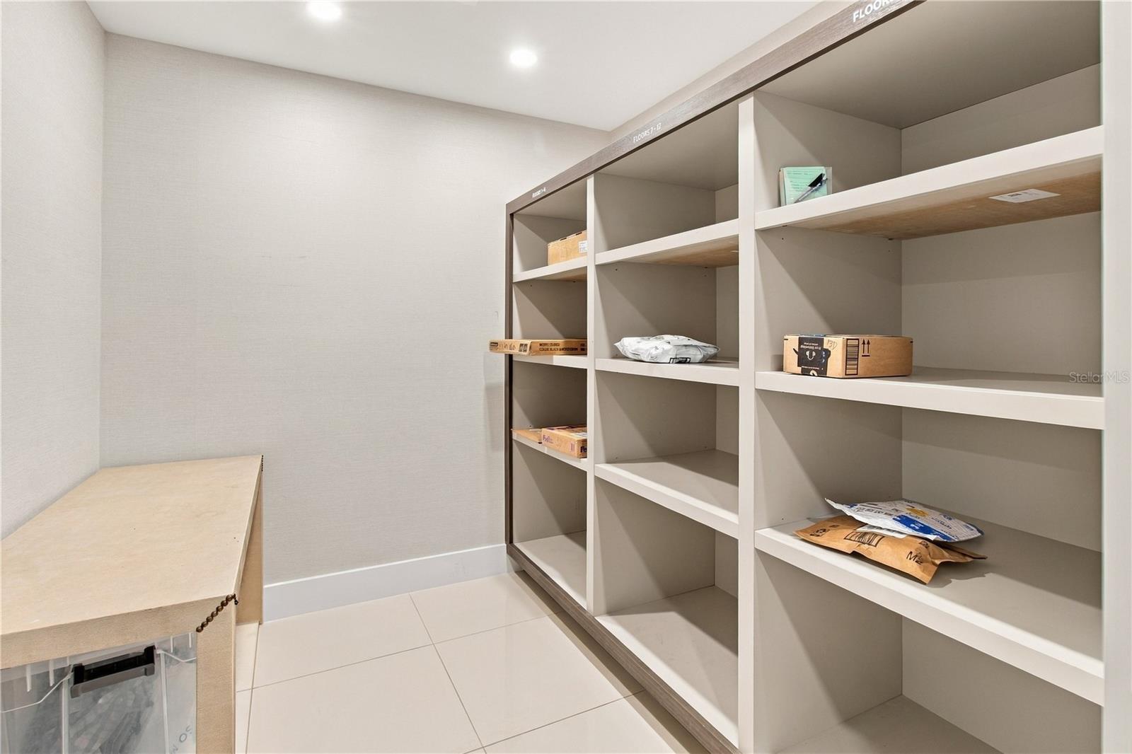 Walk-in closet with floor-to-ceiling open shelving and a low beige cabinet.