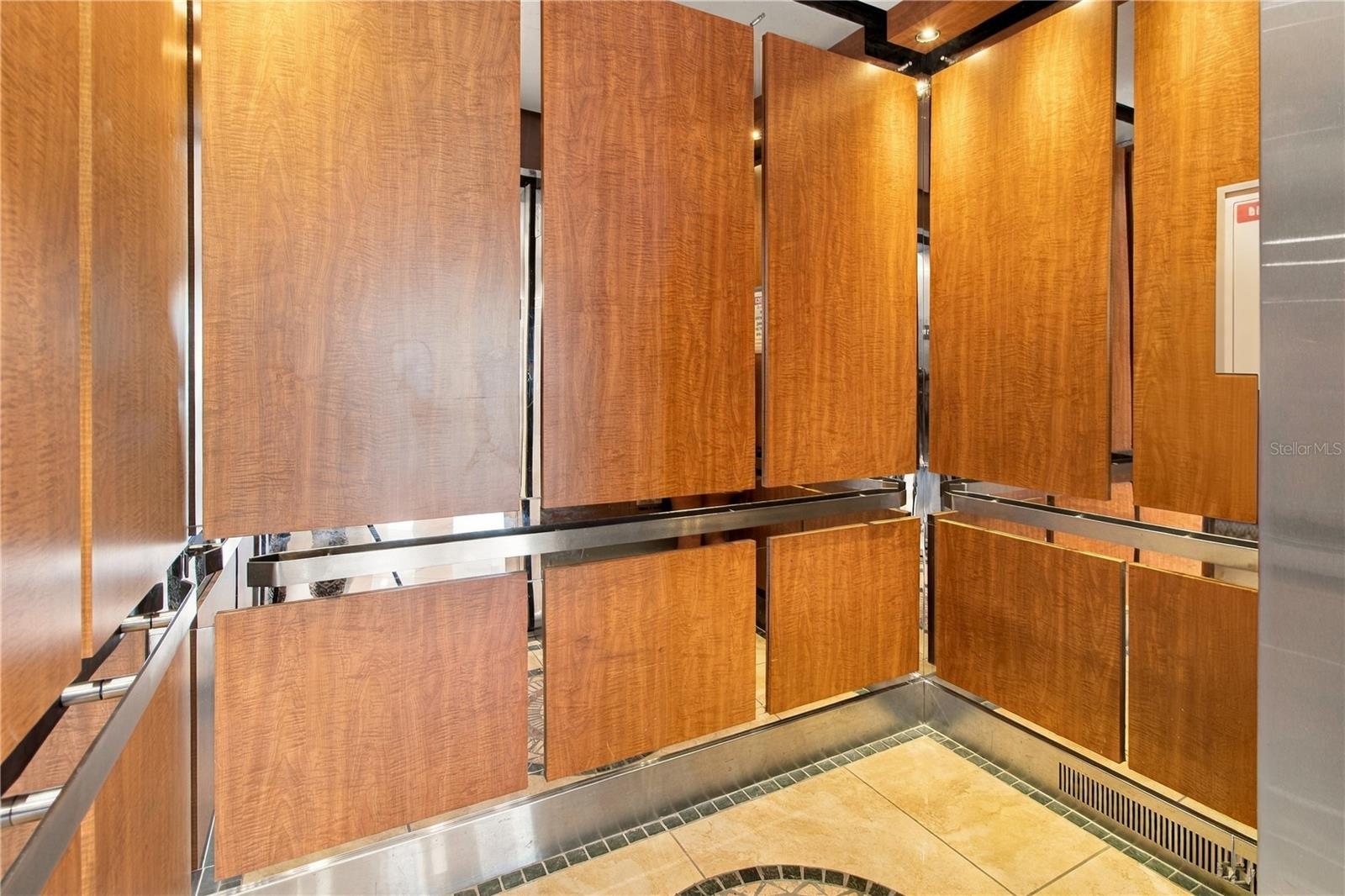 Wood-paneled elevator with mirrored surfaces and a tiled floor.