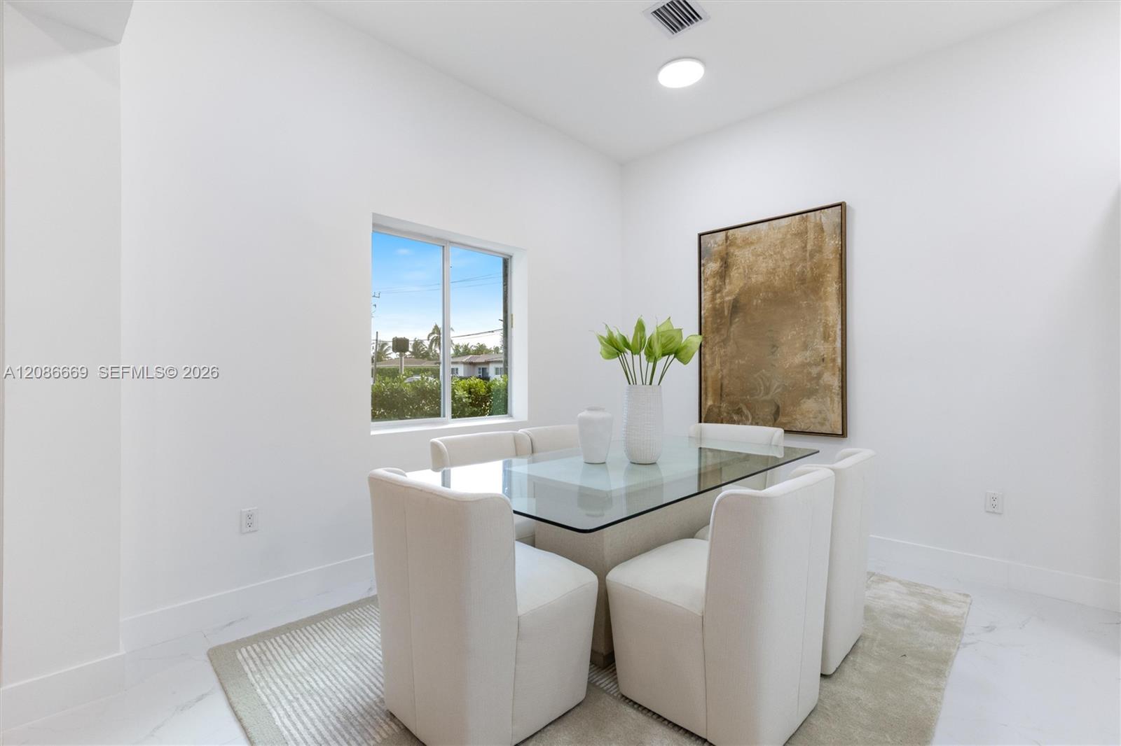 Staged dining room with a glass-top table, cream chairs, and abstract wall art.