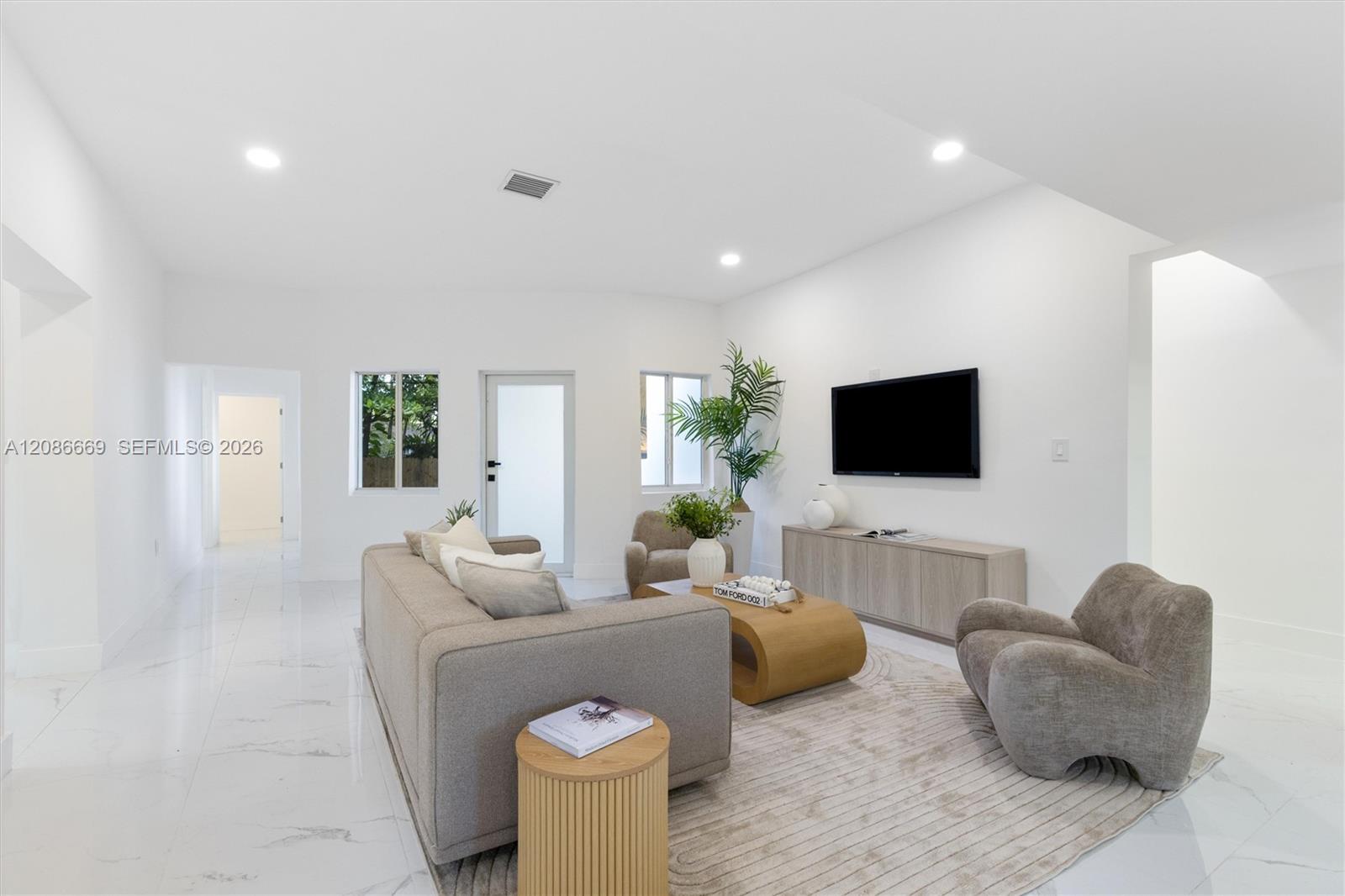 Staged living room with gray seating, a wooden coffee table, and a wall-mounted television.