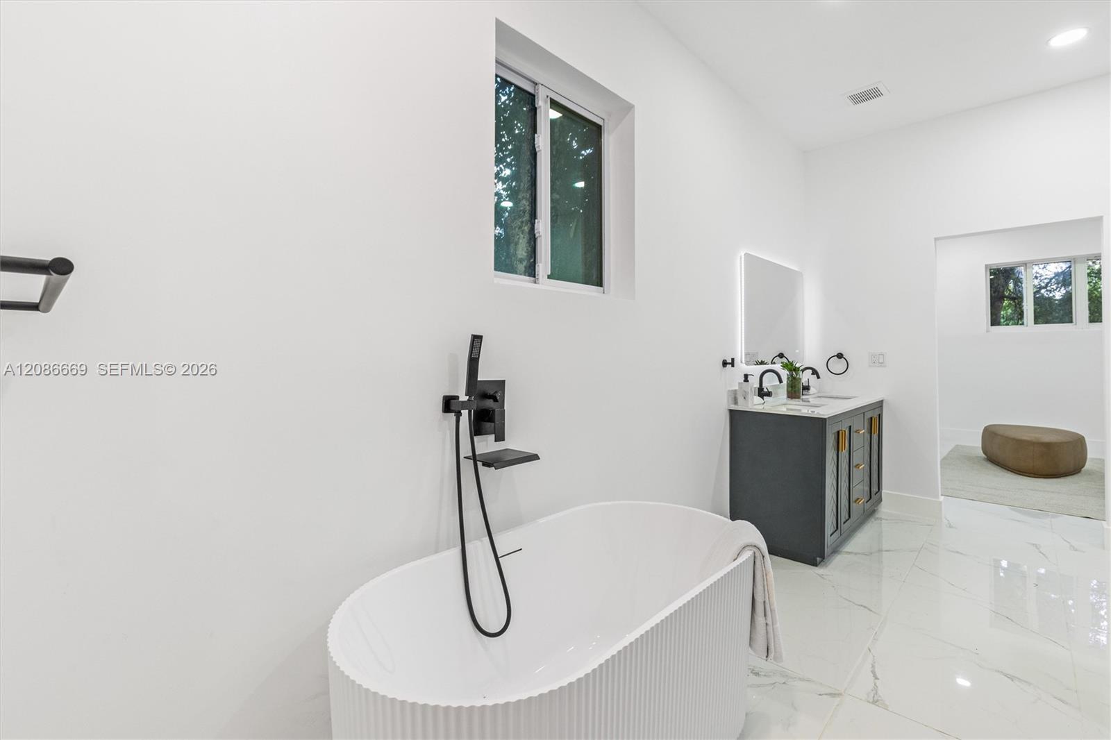 Modern bathroom with a freestanding tub, black fixtures, and a dark double-sink vanity.