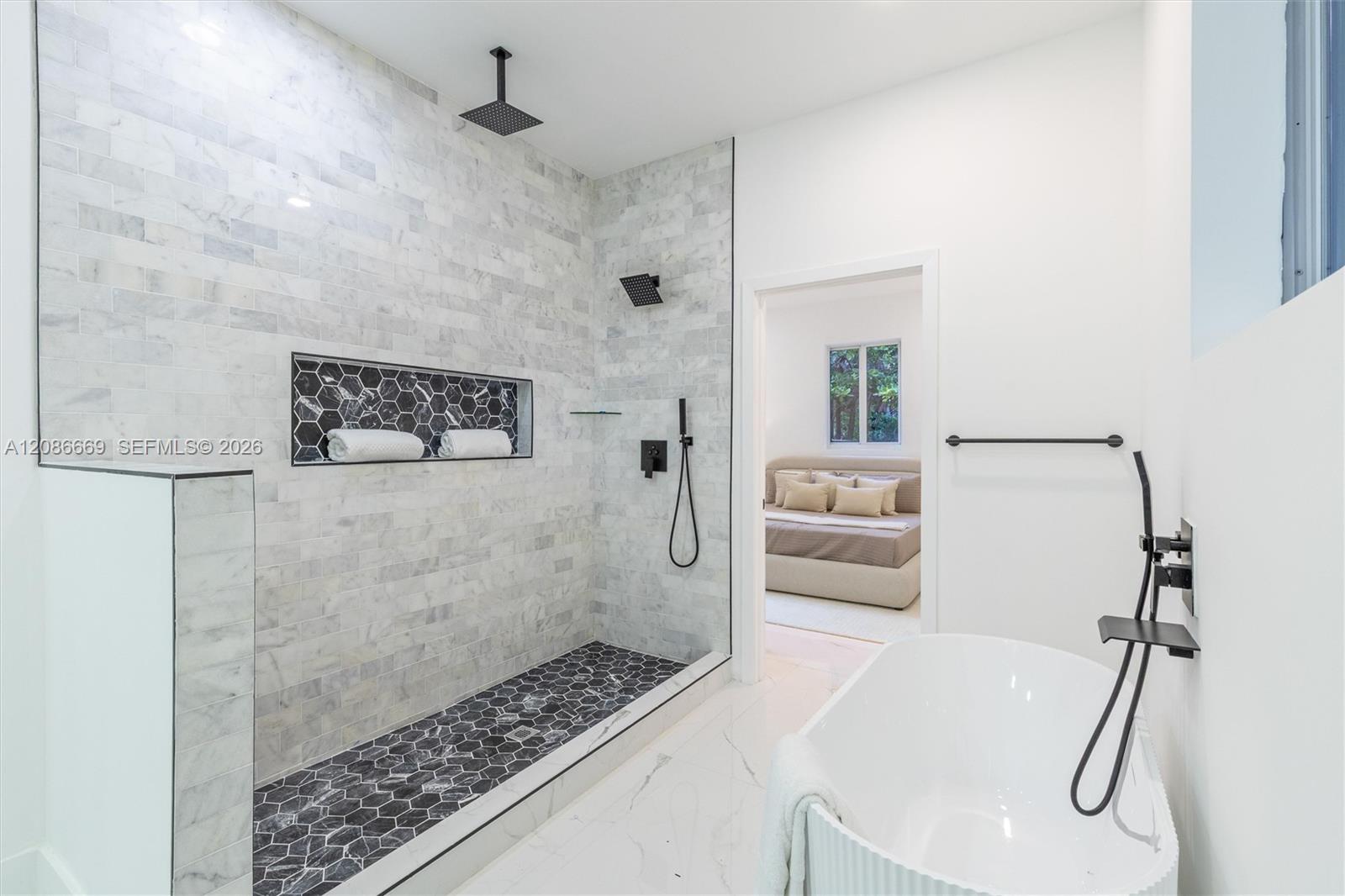 Modern bathroom with a marble walk-in shower, dark hexagonal tile accents, and a freestanding tub.