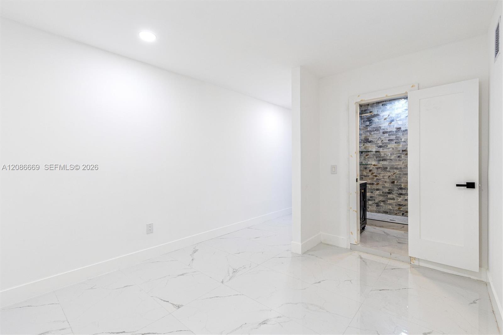 Empty white room with glossy marble-look floors and an open doorway to a tiled shower.