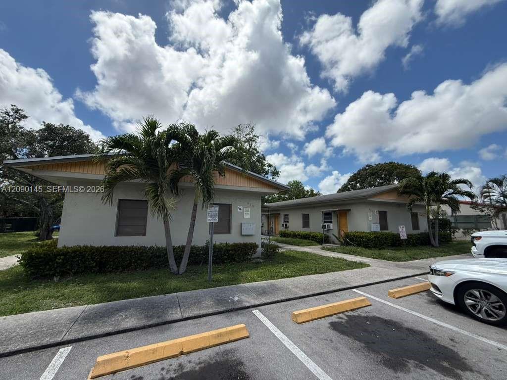 Single-story buildings with palm trees beside a small parking lot.