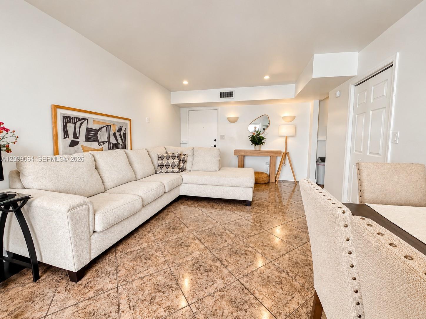 Staged living room with a cream sectional sofa, patterned tile floors, and a console table.