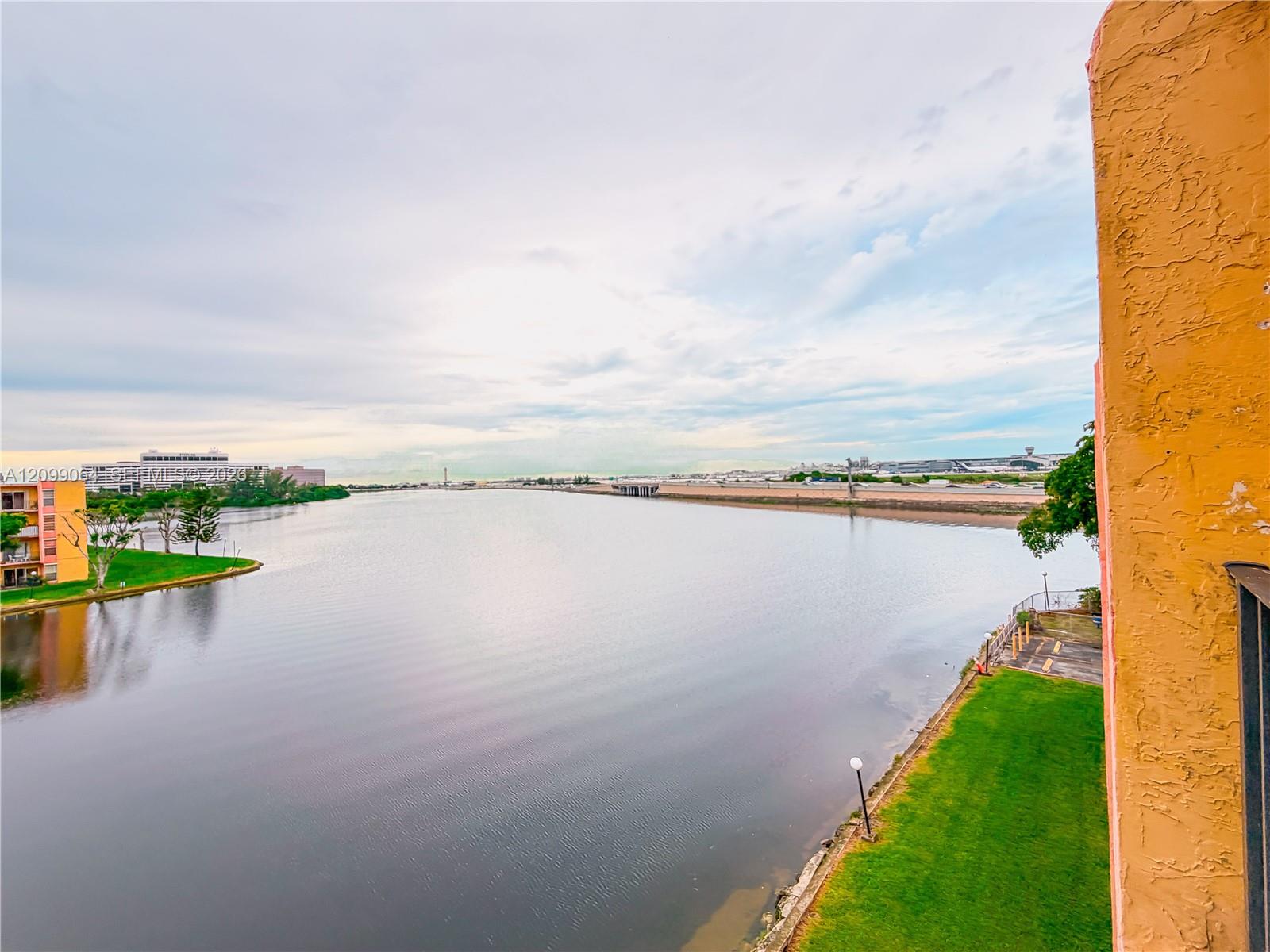 Water view from the building, framed by an orange stucco wall and grassy shoreline.