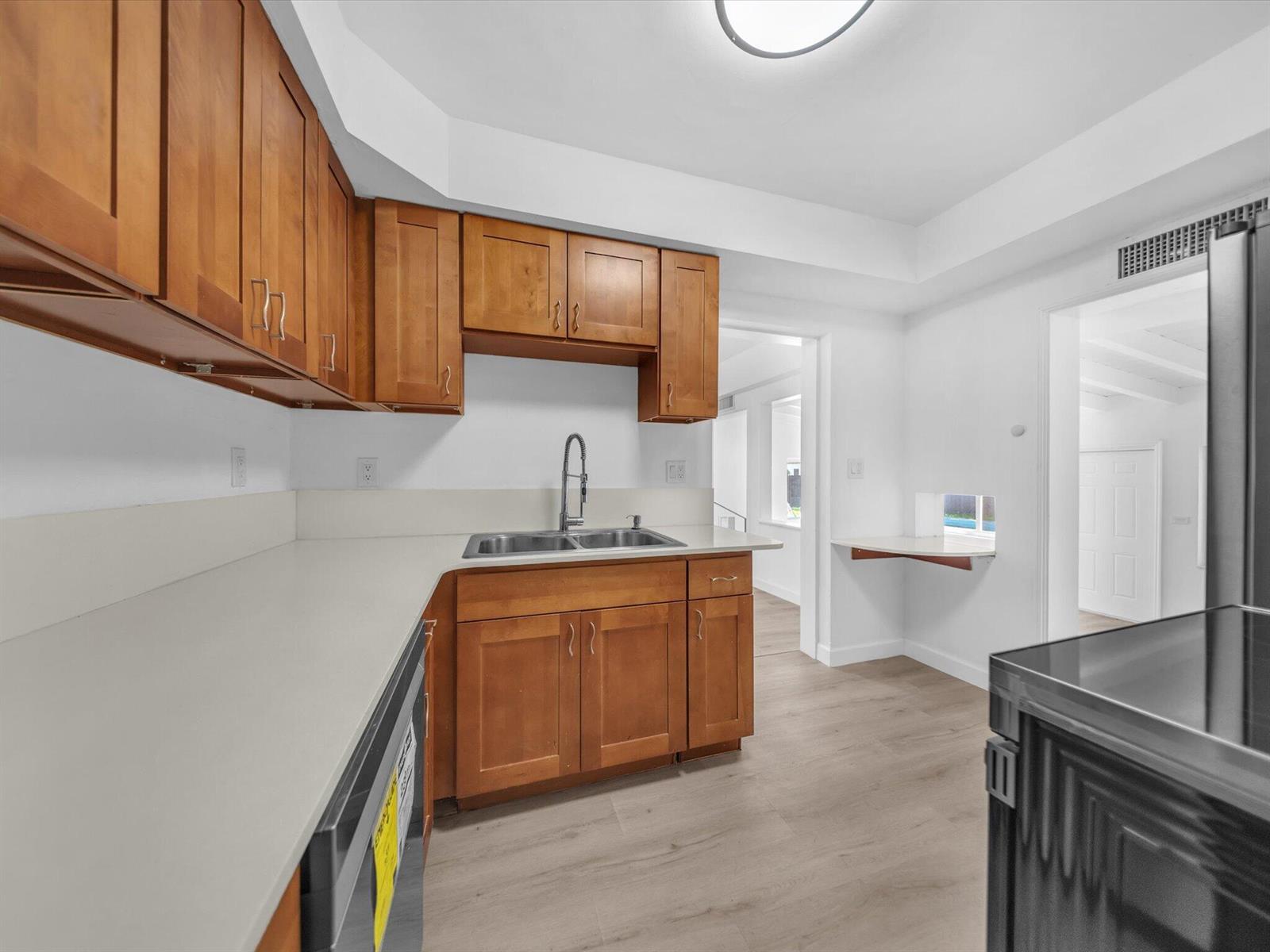 Kitchen with warm wood cabinets, white countertops, a double-basin sink, and a pass-through counter.