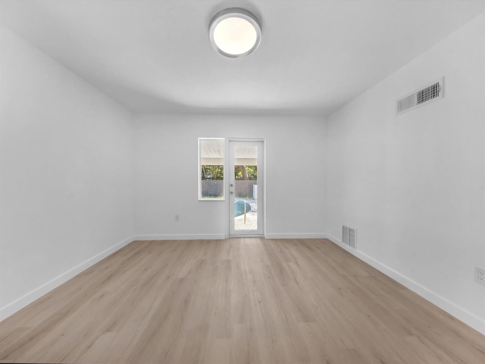 Vacant room with light wood-look flooring and a glass patio door.