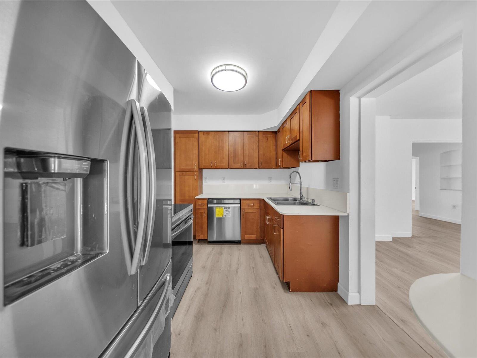 Kitchen with warm wood cabinets, white countertops, and stainless steel appliances.