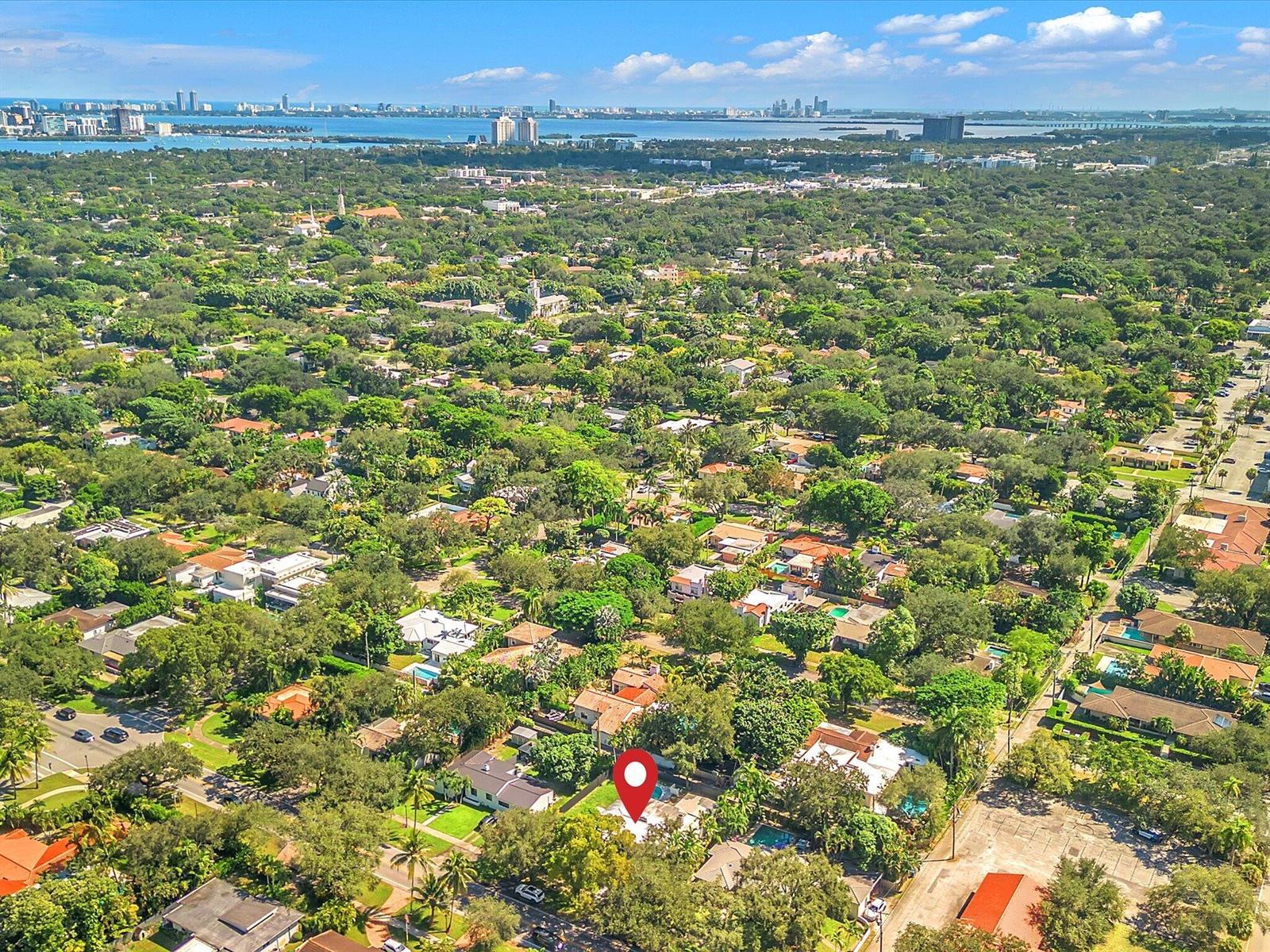 Aerial view of a leafy neighborhood, with Biscayne Bay and the Miami skyline in the distance.