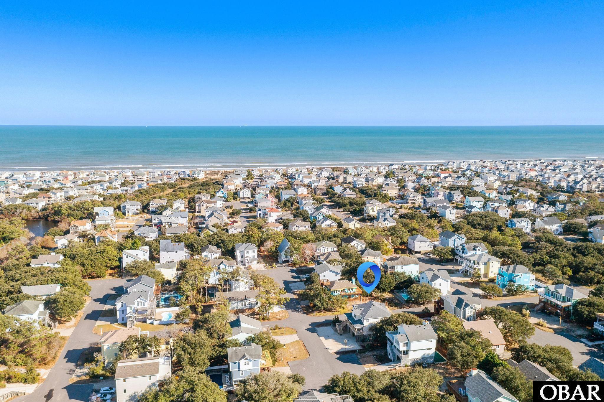Aerial view of the marked lot among coastal homes, with the ocean beyond.