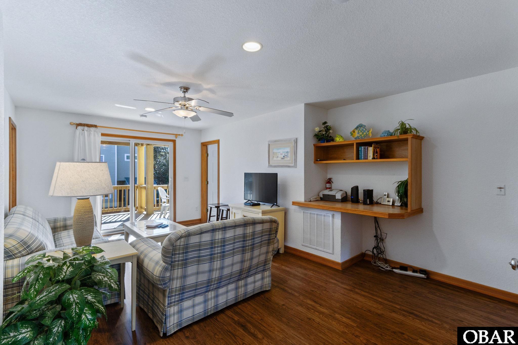 Living room with plaid sofas, a built-in wood entertainment shelf, and sliding doors to a deck.